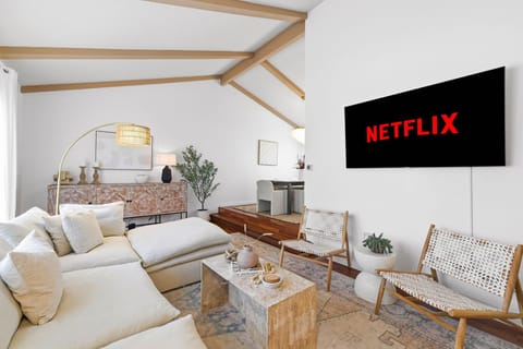 Coastal-style living room with large sofa and TV, offering a serene retreat just steps from the beach.