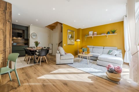 Grand salon avec canapé et fauteuils, ouvert sur la cuisine et sur la terrasse