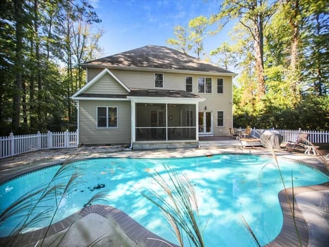 Rear exterior view shows a private backyard pool with surrounding deck space and the spacious two-story home nestled among mature trees.