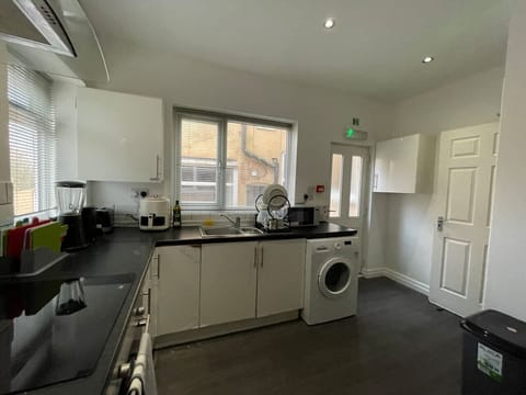A bright kitchen with white units, black worktops, and a washing machine.