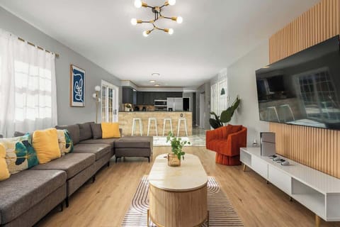 Open, airy living room w/ cozy seating, colorful accents & large windows filling the space with natural light.