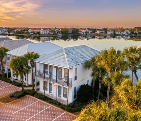 Aerial view of this waterfront community, showcasing palm-lined buildings, serene lake views, and easy access to the beach and resort-style amenities nearby.