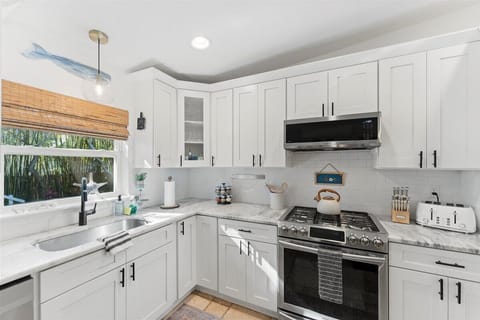 Kitchen: Bright and airy, this gourmet kitchen boasts sleek appliances and charming coastal decor!

