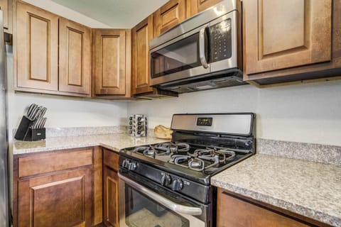 A professional-grade gas range and microwave are perfectly positioned near the integrated spice rack. The deep wood cabinetry and granite counters provide a polished and highly functional space for your stay.