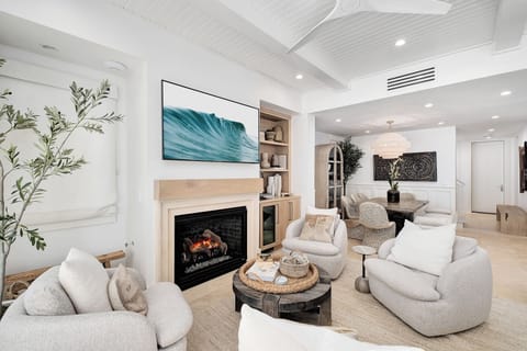 Sink into plush sofas by your crackling fireplace, where coastal art and warm textures create your perfect retreat sanctuary.