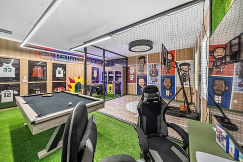 Welcome to our vibrant game room, where a sleek pool table and unique artificial grass floor create a playful atmosphere. Colorful wall art of famous athletes enhances the space, perfect for fun and friendly competition.