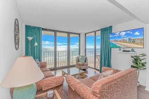 Bright and inviting living room featuring wrap-around windows, coastal décor, and breathtaking views of the shoreline.