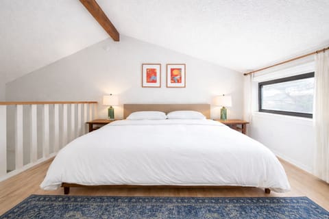 Loft bedroom with king bed, vaulted ceiling, cozy rug.