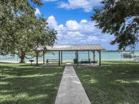 Lakefront pavilion with picnic table, outdoor seating, and charcoal grill