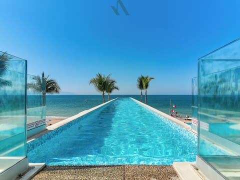 Rooftop infinity pool with uninterrupted Pacific Ocean views, sleek glass walls, and a tranquil resort atmosphere.