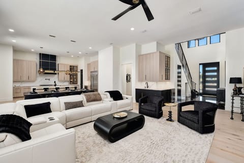 Step into your sophisticated open-concept retreat where sleek design meets comfort. Relax on plush white sofas while enjoying the modern kitchen's seamless flow.