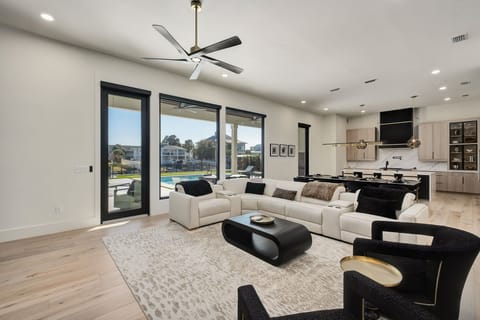 Relax in your spacious open-plan living area with plush sectional seating, modern kitchen, and stunning pool views through floor-to-ceiling windows.