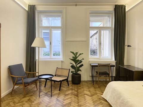Geräumiges Zimmer mit originalem Fischgrätparkett, separatem Schreibtisch und einer komfortablen Sitzecke.