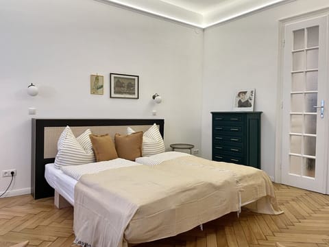 Ruhiges Schlafzimmer mit komfortablem Doppelbett, edler Bettwäsche und Vintage-Kommode für ausreichend Stauraum.