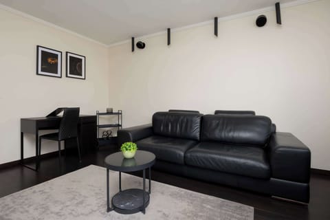Stylish living room with a black leather sofa, coffee table, and modern décor creating a comfortable relaxation space.