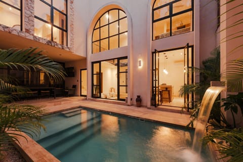 Striking villa exterior with terracotta walls, black steel-frame windows, and lush tropical garden entrance.
