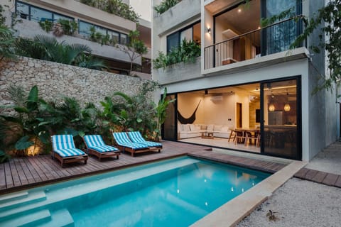 Villa exterior with private pool terrace, sunloungers, outdoor dining, and tropical tree canopy.