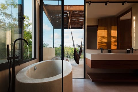 Open-air spa terrace with freestanding soaking tub, hammock, and dense jungle surroundings.