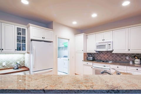 The Fairway House features a spacious, renovated kitchen with tiled backsplash and white cabinetry.