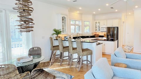 The dining area has seating for four at the table and four at the bar, with additional seating for six just outside the french doors. It is adjacent to the kitchen.
