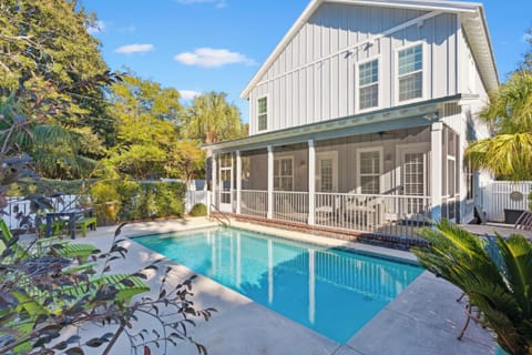 Beautiful coastal property with private swimming pool surrounded by tropical landscaping and covered front porch.