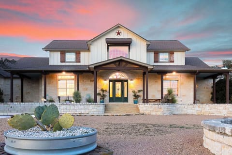Stunning Texas-style property featuring limestone and wood accents beneath a breathtaking sunset sky.