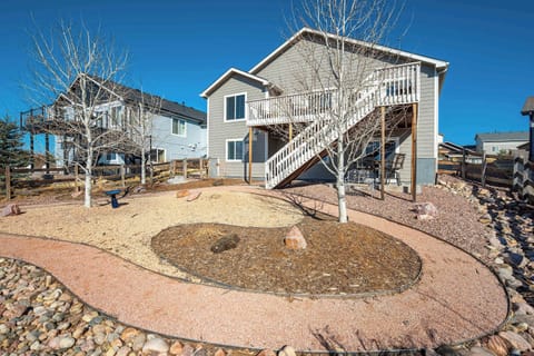 The backyard features a quiet and open layout with winding gravel paths and small trees. This outdoor space offers a shaded walk-out patio and stairs leading to the elevated wood deck for easy access to the main level.