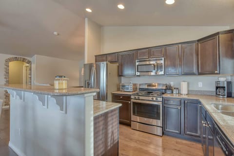 The kitchen is equipped with stainless steel appliances, including a large refrigerator and a built-in microwave. Dark cabinetry provides ample storage, while the light-colored countertops offer a clean and practical workspace for preparing meals.