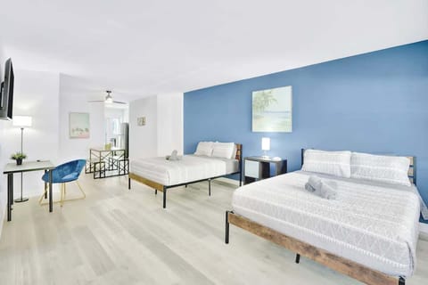 Open living area with 2 queen beds and a workspace under the TV.