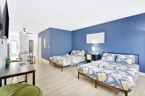 Open layout with 2 queen beds, Smart TV, and workspace under the TV with table and 2 chairs.