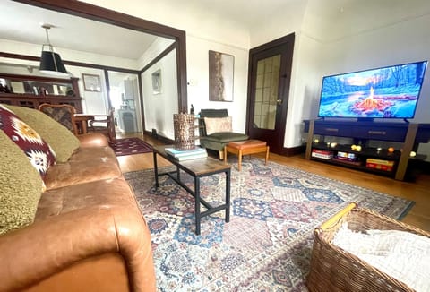 Cozy living room with Smart TV, original Craftsman details, and warm lounge seating—perfect for relaxed evenings after exploring the city.