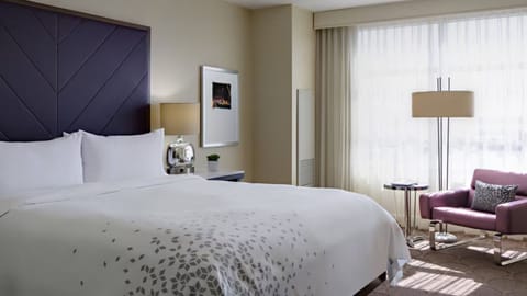 Unwind in crisp linens beneath a dramatic modern headboard.
