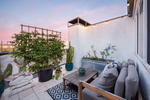 Private outdoor patio with cozy seating, string lights, and lush greenery, perfect for relaxing at sunset.