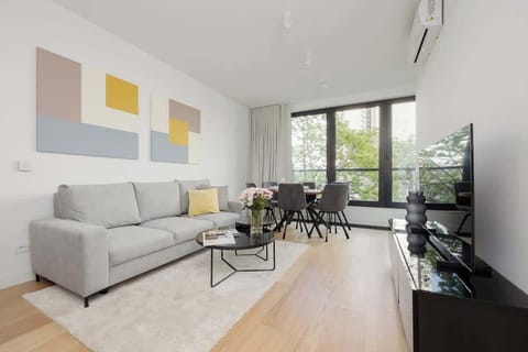 Elegant and bright living room with dark coffee table, television with access to cable channels and functional dining area with table and chairs.