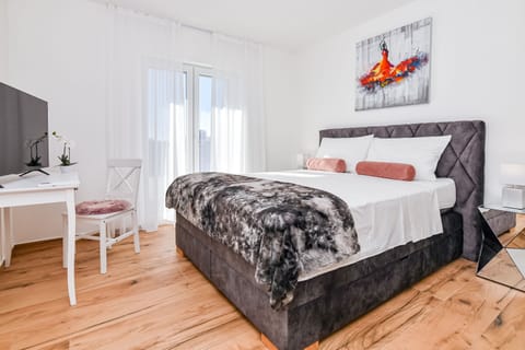 Stylish bedroom with box spring bed, TV, desk, and terrace access.