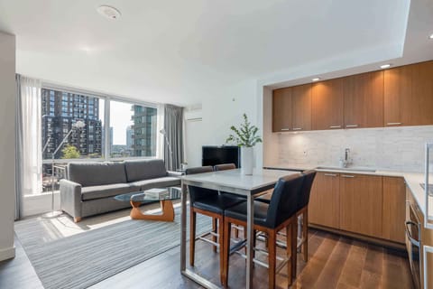 Open-concept studio featuring a modern kitchen, dining area, and comfortable living space with large windows.