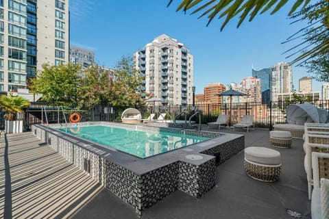 The rooftop pool area is a stylish retreat, surrounded by city views and lush landscaping, featuring comfortable lounge chairs that promise a perfect day of leisure.