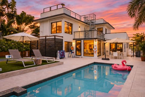 Resort-style backyard at sunset—private pool & spa, lounge chairs + umbrella seating, and a rooftop deck for golden-hour views.