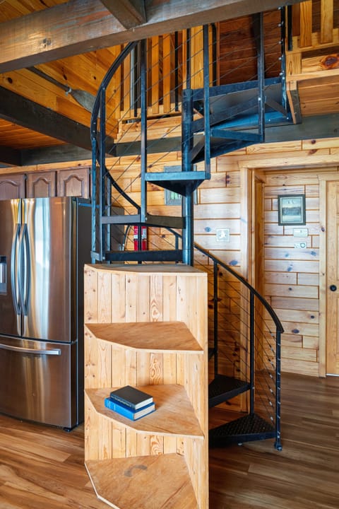 Sleek spiral stairs meet warm cabin charm—where modern design and cozy vibes rise together.