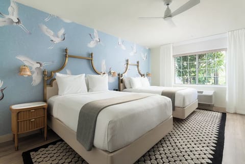 Unwind in bright double-queen comfort with whimsical crane wallpaper.