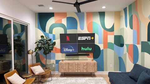 A bold, custom mural sets the tone in this living space, paired with cozy seating and a big-screen setup for the perfect night in.