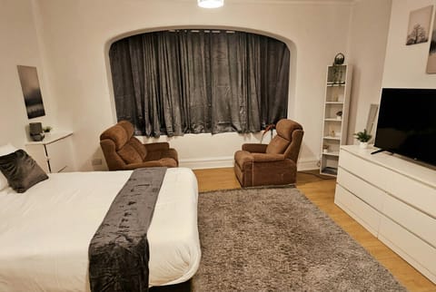 Spacious master suite with arched bay window, twin armchairs, and a king bed to unwind in style.