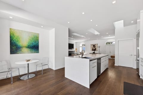 Bright, open-concept kitchen with waterfall island and skylights—seamlessly flowing into stylish living and dining spaces.