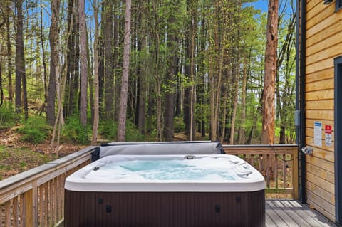 Private deck with a relaxing hot tub nestled among the trees.