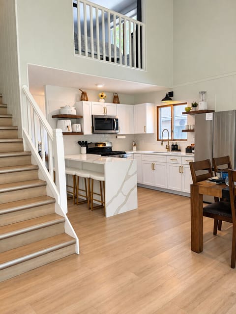 Bright loft-style kitchen with waterfall island, dining area, and airy ceilings