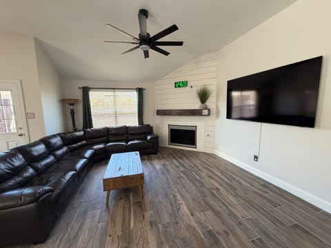 Open-concept living room with plush seating, sleek 75" Smart TV & digital clock