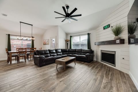 Open-concept living room with plush seating, sleek 75" Smart TV & digital clock