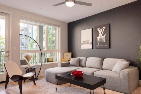 Spacious living room featuring a cozy L-shaped sofa, a full-size air mattress, and a 65" Smart TV with preloaded access to Netflix, Hulu, and Disney+, all set up for your enjoyment.