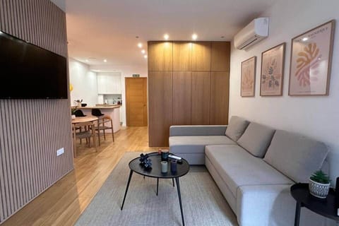 Salón con sofá chaise longue, Smart TV y cocina al fondo