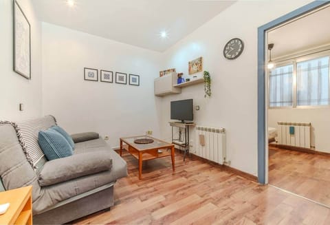 Salón con sofá, TV y paso al dormitorio